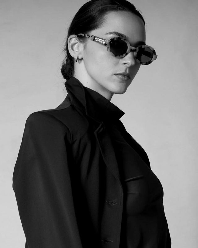 A model in a tailored black CALLIDAE jacket and sunglasses