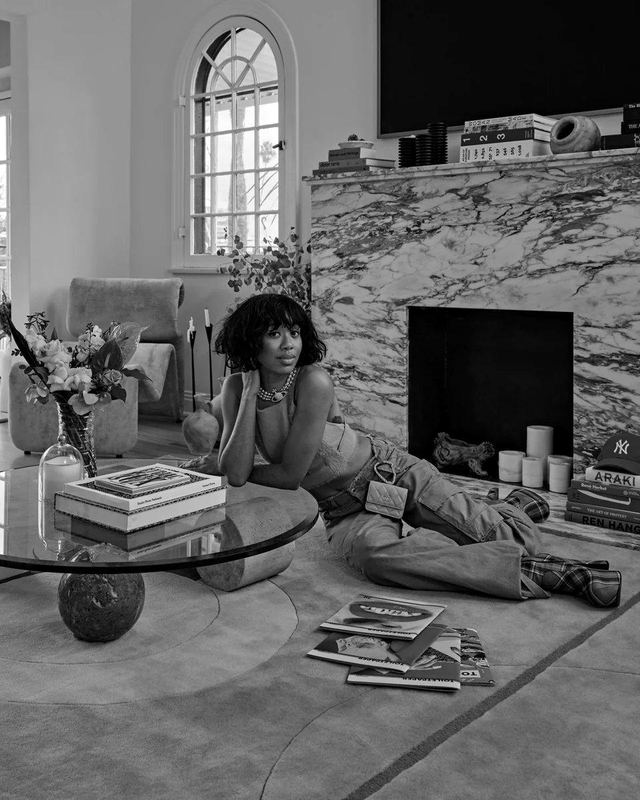 A model lounging beside a marble fireplace in a living room styled with Pieces furniture