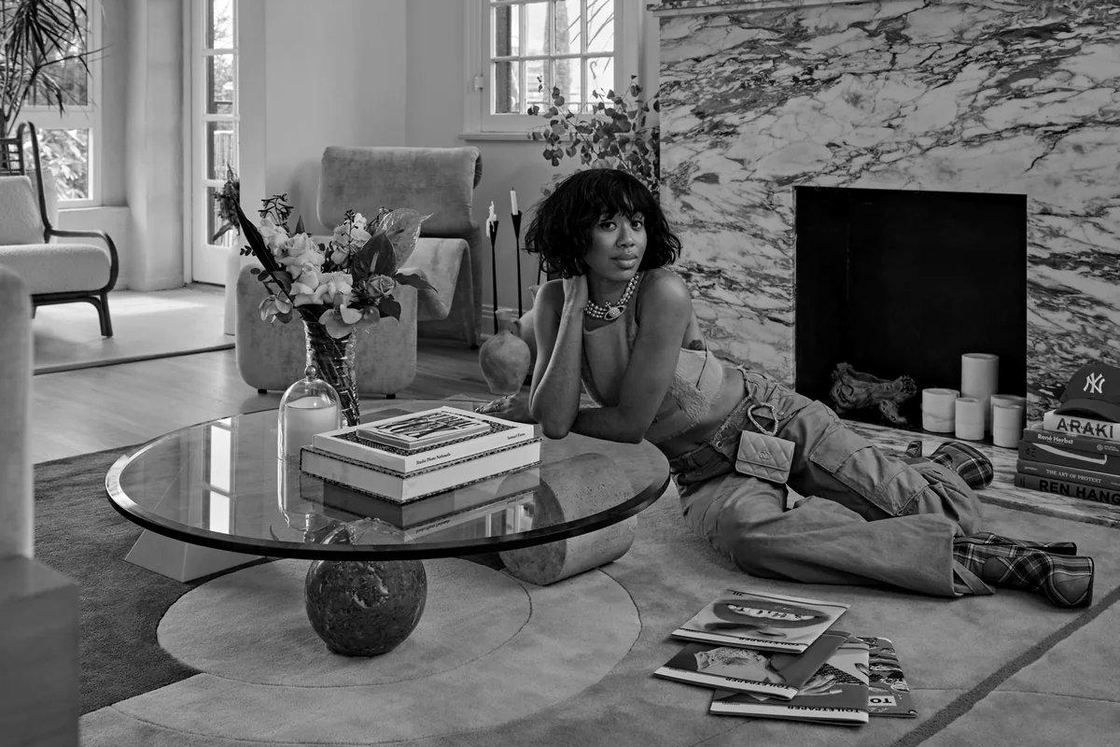 A model lounging on a rug beside a glass coffee table in a living room styled with Pieces furniture