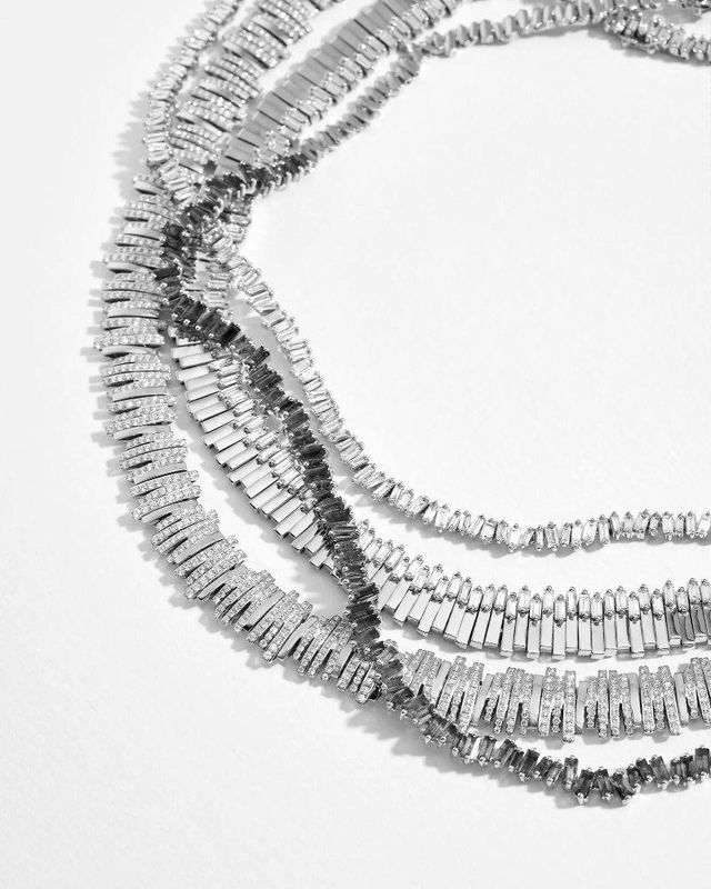 Strands of Suzanne Kalan baguette-diamond necklaces laid on a white surface